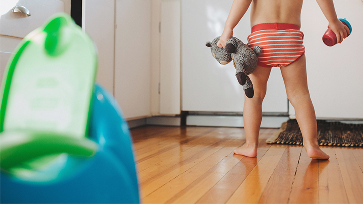 potty training tips, toddler boy in big boy pants with potty in foreground